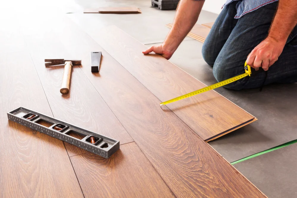 Hands of a carpenter fitting engineered wood floor panels together